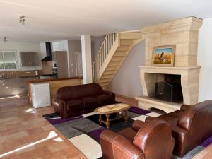 a living room with leather furniture and a fireplace at Domaine clos et arboré de 3 ha avec deux maisons in Lamothe-Montravel