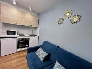 a living room with a blue couch and a kitchen at Superbe appartement 1 bedroom équipée 2P Parc des Princes in Boulogne-Billancourt