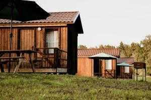 a wooden cabin with a table and an umbrella at Kempings Adamova 