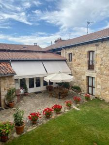 un patio con sombrilla y flores en Peñasalve, en Villamoñico