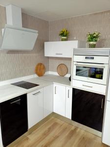 a kitchen with white cabinets and black appliances at Ángeles home in El Vendrell