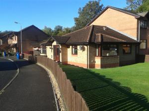 a brick house with a fence next to a yard at Dingieshowe Cottage in Lennoxtown +21 photos