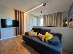 sala de estar con sofá azul y almohadas amarillas en Halo Apartments, en Wroclaw