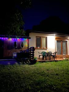 une maison avec une terrasse éclairée la nuit dans l'établissement Wiolinkowo, à Sarnaki