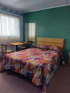 Motel du Cap St-Yvon في Cloridorme: غرفة نوم بسرير وطاولة وكرسي