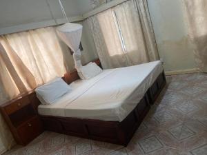 uma pequena cama num quarto com uma janela em One World Village Guesthouse em Bakau