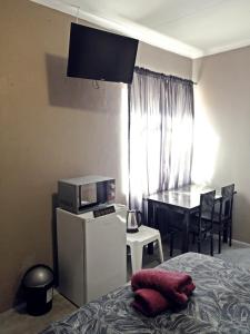 Schlafzimmer mit einem Bett, einer Mikrowelle und einem Tisch in der Unterkunft Ambiente Budget Accommodation in Upington