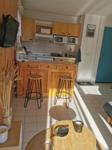 昂布朗的住宿－Appartement T2 en résidence, centre ville d'Embrun，厨房配有木制橱柜和一张带凳子的桌子