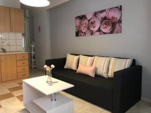 a living room with a black couch and a table at Pink Rose Apartment in Néa Péramos
