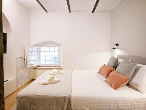 ein weißes Schlafzimmer mit einem großen Bett mit orangefarbenen Kissen in der Unterkunft Casa Primo in Cortona