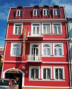a red building with white windows on a street at Marani Hotel in Batumi