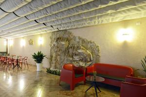 a restaurant with red chairs and a stone wall at Best Western Hotel Martello in Lampedusa