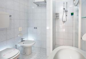 Baño blanco con aseo y lavamanos en Hotel Vela d'Oro, en Rímini