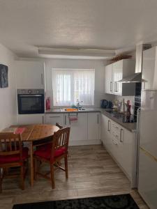 a kitchen with a wooden table and chairs and a table and a kitchen with white at Gower Cottage in Reynoldston