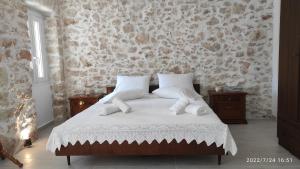 a bedroom with a bed with white sheets and pillows at Suites-Xenonas "Alexandra's Coffee House" in Volímai