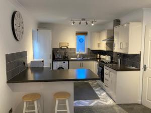 a kitchen with a counter and two stools in it at Modern 2 Bedroom Ground Floor Apartment with Parking Ripon City Centre in Ripon