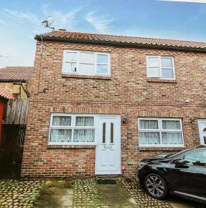 a brick house with a car parked in front of it at Modern 2 Bedroom Ground Floor Apartment with Parking Ripon City Centre in Ripon
