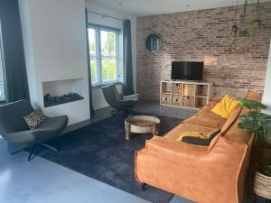 a living room with a couch and a tv at Casa Morreni, luxe villa met sauna in Voorthuizen