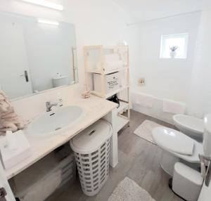 a white bathroom with a sink and a toilet at Alojamento local "CASA BRANCA" in Albufeira