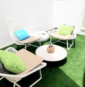 un groupe de chaises et de tables sur un sol vert dans l'établissement Alojamento local "CASA BRANCA", à Albufeira