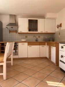 una cocina con armarios blancos y una silla. en Haus Waldfrieden, en Bischofswiesen
