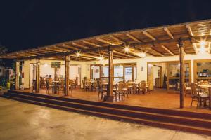 un restaurante con mesas de madera y sillas por la noche en Hotel El Condor, en Paracas
