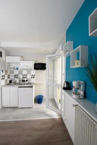 a kitchen with white cabinets and a blue wall at Superbe 2 pièces - proche de Paris in Villeneuve-la-Garenne