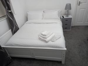 a bed with two piles of towels on it at Garswood Road House in Manchester