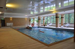 duży basen w budynku z dwoma osobami w nim w obiekcie Hotel Mir-Jan SPA w mieście Lądek-Zdrój