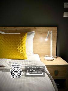 ヴィスワにあるRezydencja Pod Ochorowiczówką B&Bのベッドルーム1室(黄色い枕とランプ付きのベッド1台付)