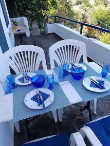 a table with plates and blue glasses on a balcony at Blue Vista Ikaria in Arethousa