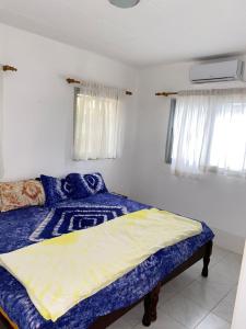 a bedroom with a bed with blue sheets and windows at Swiss Garden House in Kerr Sering With Full Private Compound in Amdalai