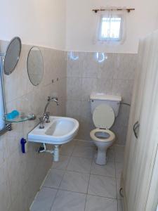 a bathroom with a toilet and a sink and mirror at Swiss Garden House in Kerr Sering With Full Private Compound in Amdalai