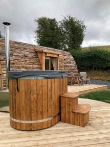 a wooden cabin with a hot tub and a bench at Delor - Bryntalch Glamping Pods in Montgomery