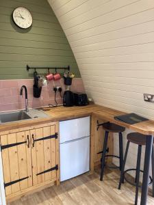 a kitchen with a sink and a clock on the wall at Delor - Bryntalch Glamping Pods in Montgomery