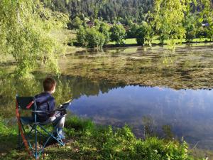 Ein Junge, der auf einem Stuhl sitzt und einen See ansieht. in der Unterkunft Belle maison proche de la ville et du lac in Belcaire