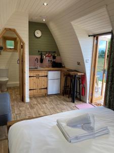 a bedroom with a bed and a kitchen in a room at Delor - Bryntalch Glamping Pods in Montgomery