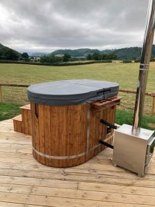 a hot tub on a wooden deck with a field at Delor - Bryntalch Glamping Pods in Montgomery