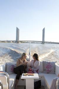 two women sitting on a boat on the water at Château Grattequina Hôtel in Blanquefort