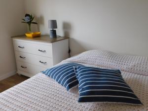 a bed with a blue pillow and a dresser at NiaAzoreanApartments2, aconchegante e confortável! in Horta