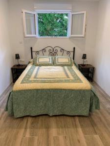 een slaapkamer met een bed met een groene deken en een raam bij Appartement 2 personnes proche plage(900m) dans une maison individuel. in Hendaye