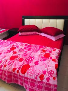 a bedroom with a pink bed with red sheets and pillows at Homestay Teratak Saazlina in Seremban