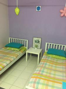 a bedroom with two beds and a table at Homestay Teratak Saazlina in Seremban