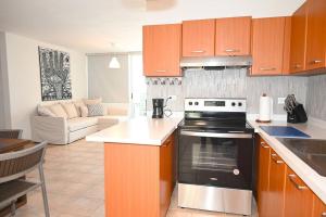 a kitchen with wooden cabinets and a stove top oven at New Remodeled Ocean view, Beach Front Apartment in Arecibo