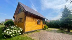una pequeña cabaña de madera en un patio con flores en Domek Morski 2C, en Łukęcin