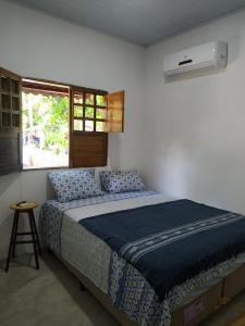 um quarto com uma cama com um edredão azul e uma janela em Casa Recanto das Mangueiras Japaratinga - Alagoas em Japaratinga