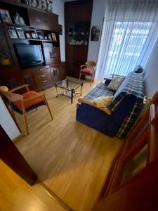 uma sala de estar com um sofá azul e uma televisão em APARTAMENTO CENTRO BURGOS em Burgos