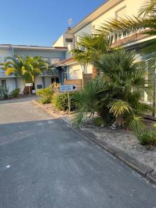 a street sign in front of a building with palm trees at Home Place Apartments - Gujan Arcachon in Gujan-Mestras