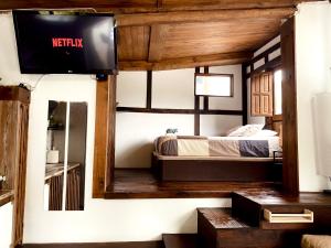 1 dormitorio con 1 cama y TV en la pared en Casita rústica en Cambre