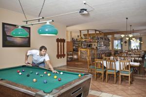 a man playing a game of pool in a restaurant at Wellness Hotel Marlin in Nová Pec